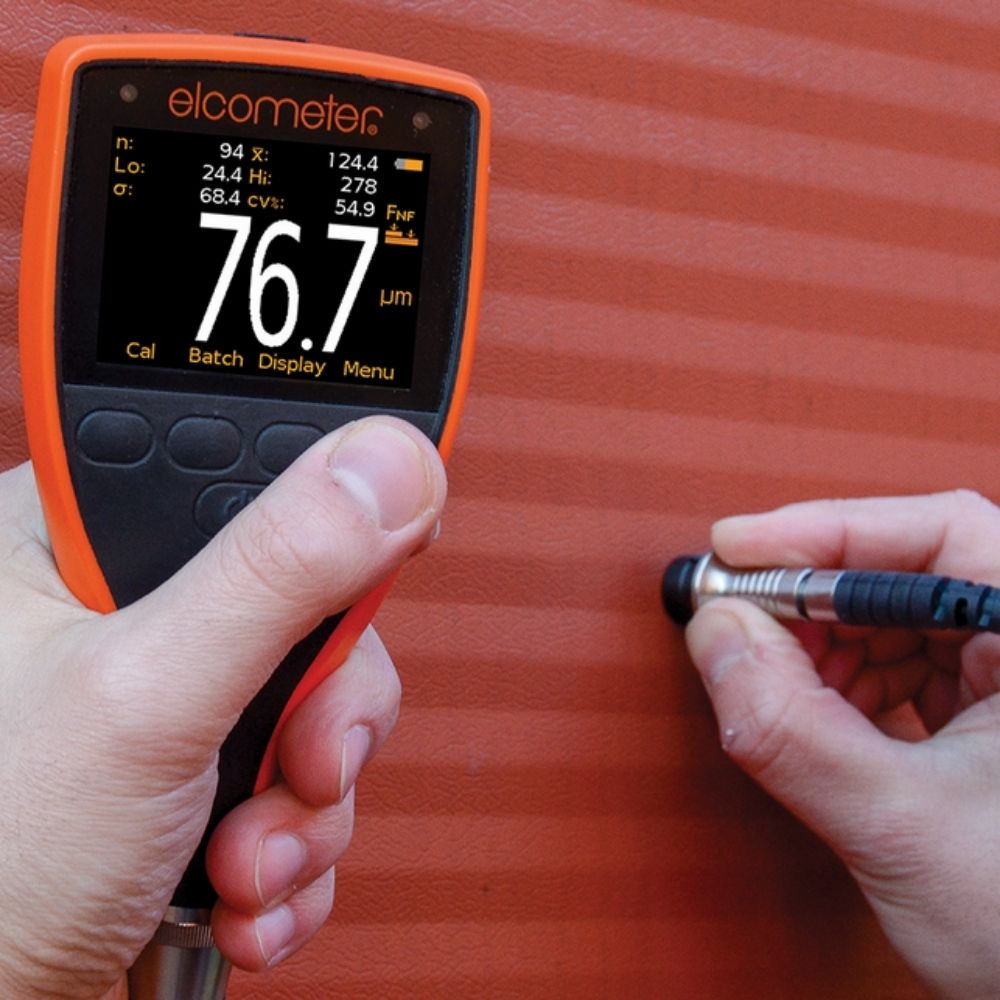 Elcometer 456 Separate Coating Thickness Gauge measuring powder coated surface, industrial paint thickness tester showing 76.7 µm DFT on metal component for quality control.