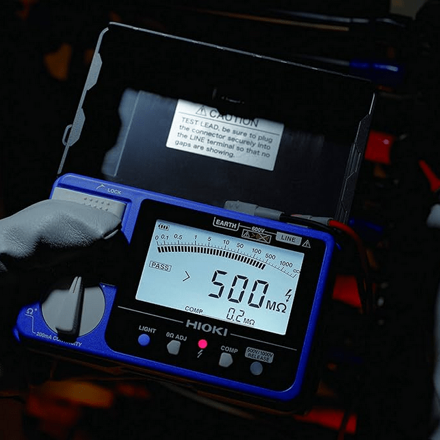 Technician using the HIOKI IR4059 insulation tester to measure insulation on a transformer, with a 500 MΩ reading visible on the display.