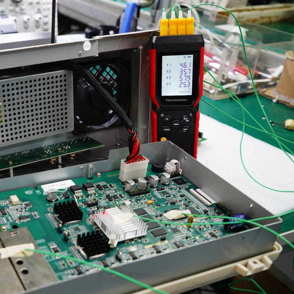 UNI-T UT325F 4-channel temperature data logger monitoring thermal outputs on a large electronic circuit board for quality control testing in Sri Lanka.