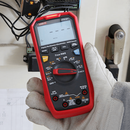 UNI-T UT61E+ performing safety checks in NCV mode near a large capacitor bank, illustrating utility for power distribution maintenance and high-voltage electrical safety.