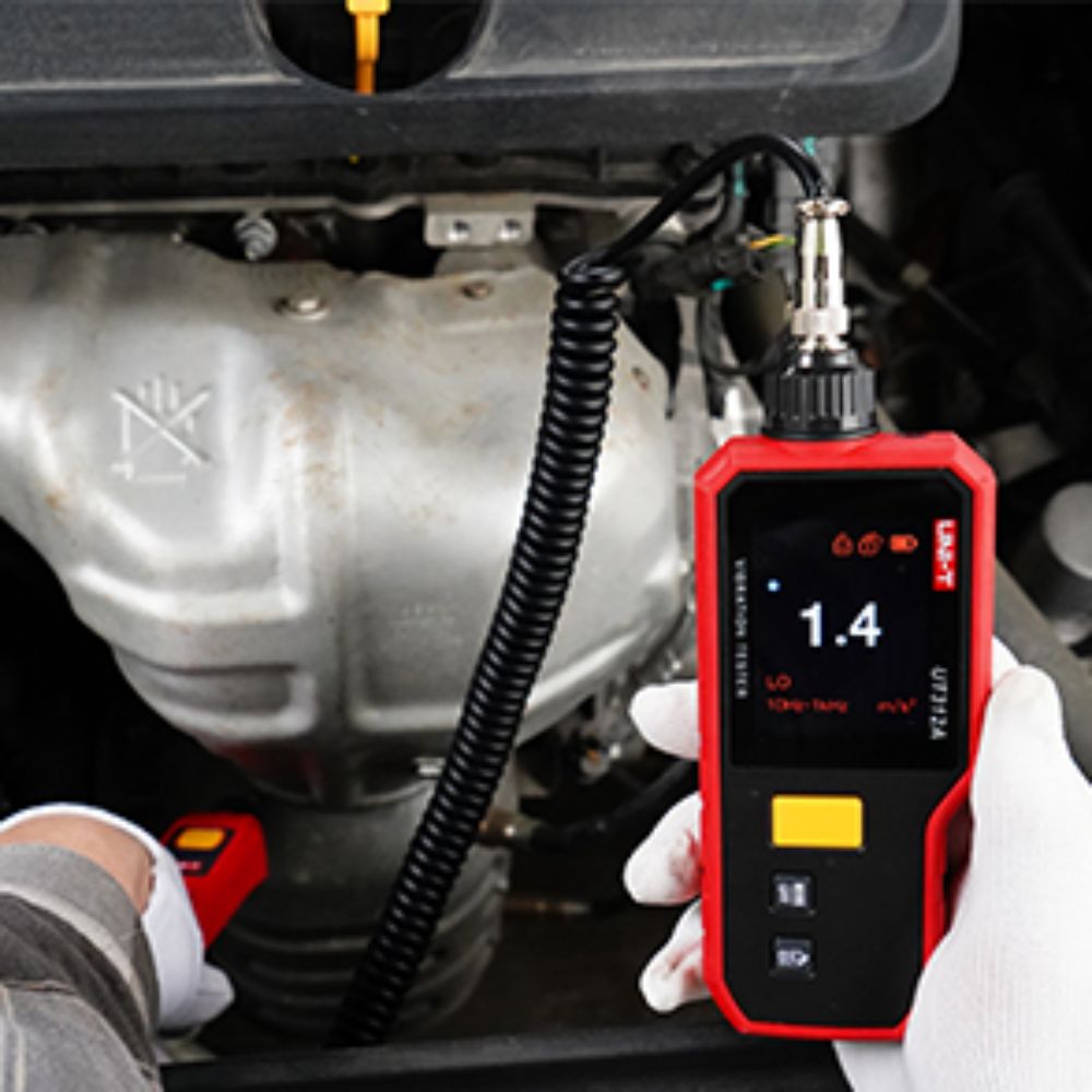 The UNI-T UT312A portable vibration tester being used for automobile engine diagnostics to detect structural unbalance and mechanical faults.