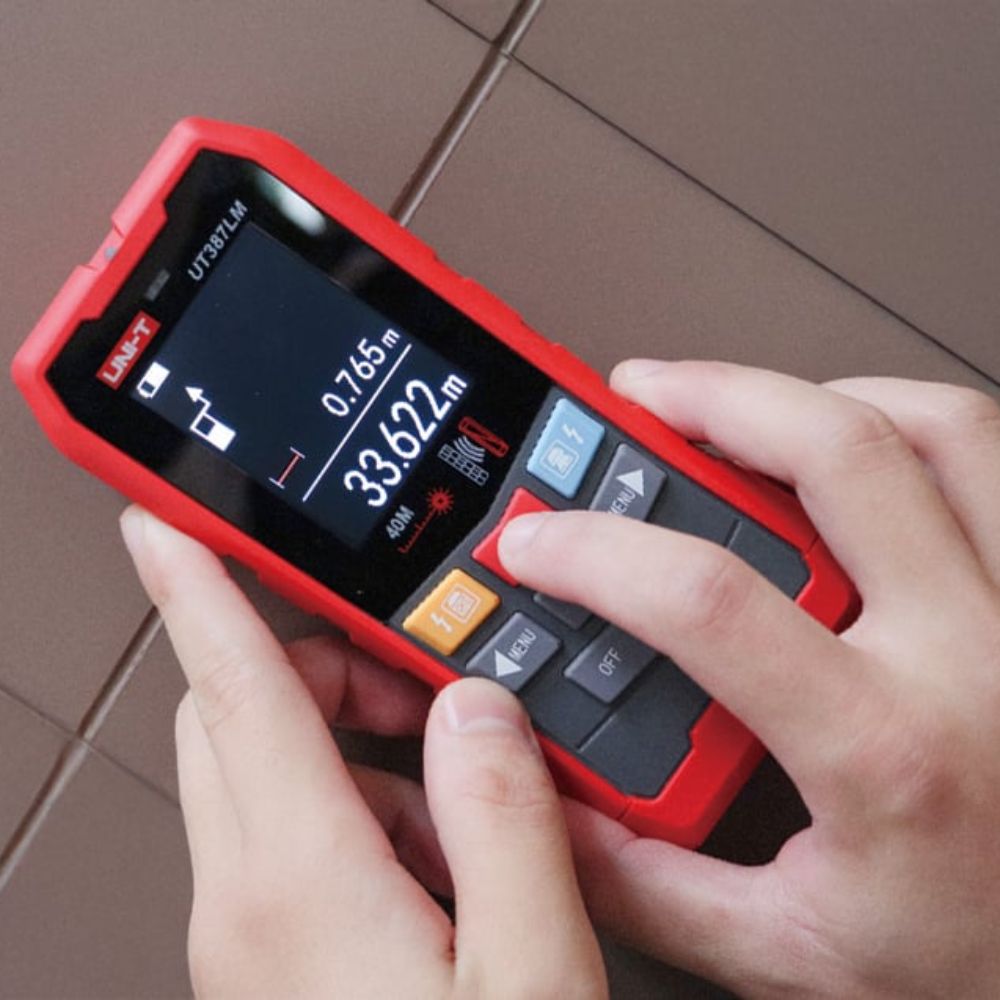 Contractor using the UNI-T UT387LM on the floor to detect hidden pipes and measure room dimensions using the built-in laser distance function.