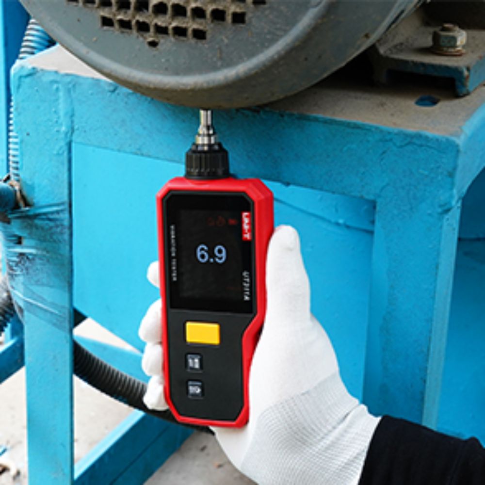 Technician measuring electric motor vibration with the UNI-T UT311A handheld tester to monitor bearing health and support preventive maintenance.