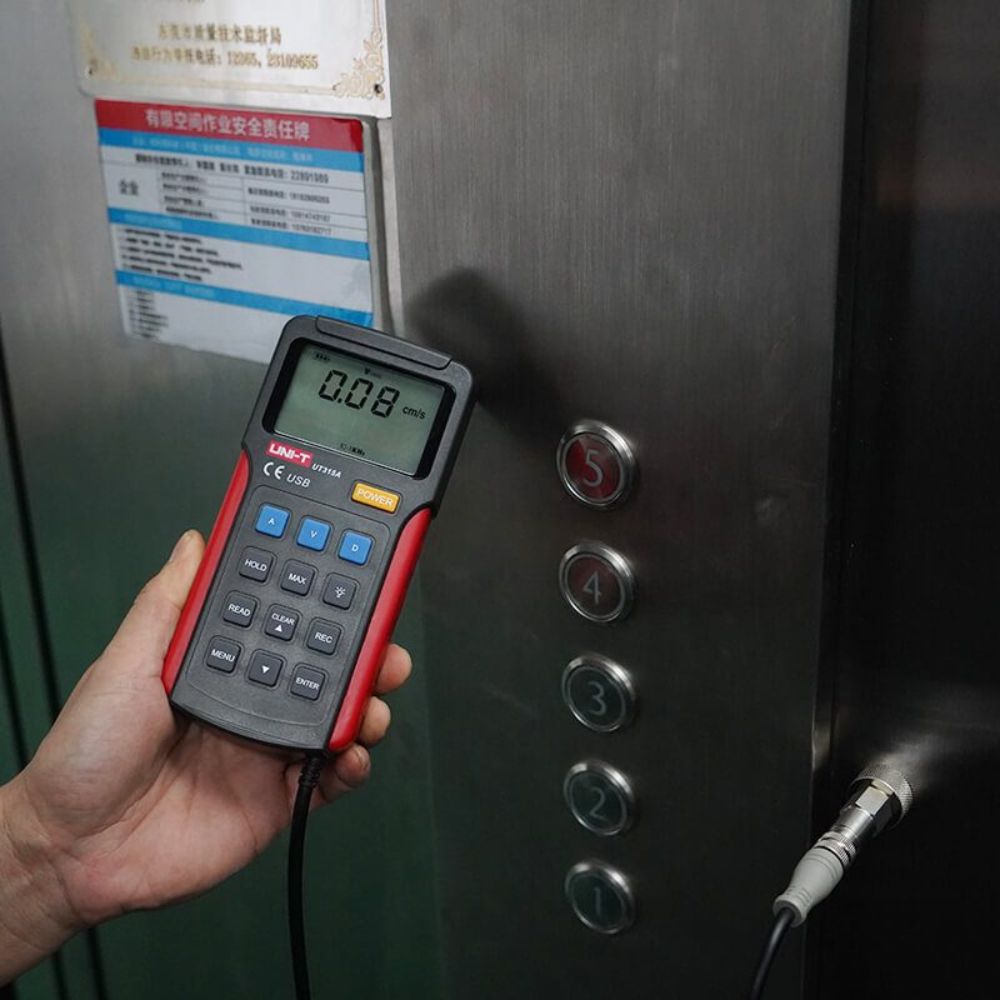 Technician testing elevator roller bearing vibrations using the UNI-T UT315A digital tester to ensure safe, smooth mechanical operation and log maintenance data.