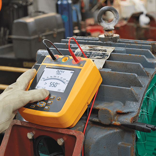 Technician testing motor insulation resistance with FLUKE 1537 insulation tester showing 550 gigaohm reading and test leads connected