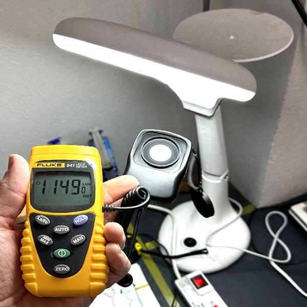 A person using the FLUKE 941 lux meter to measure indoor illumination levels, capturing a reading of 1149 lux under a bright light source.