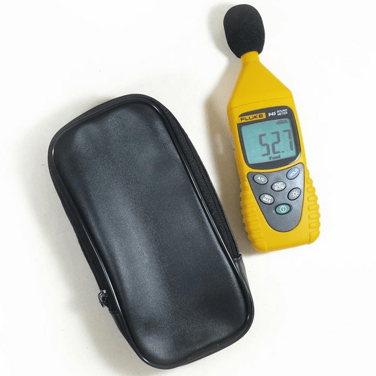 Fluke 945 digital decibel meter displaying a 52.7 dBA reading on its screen, placed next to its portable soft carrying case.