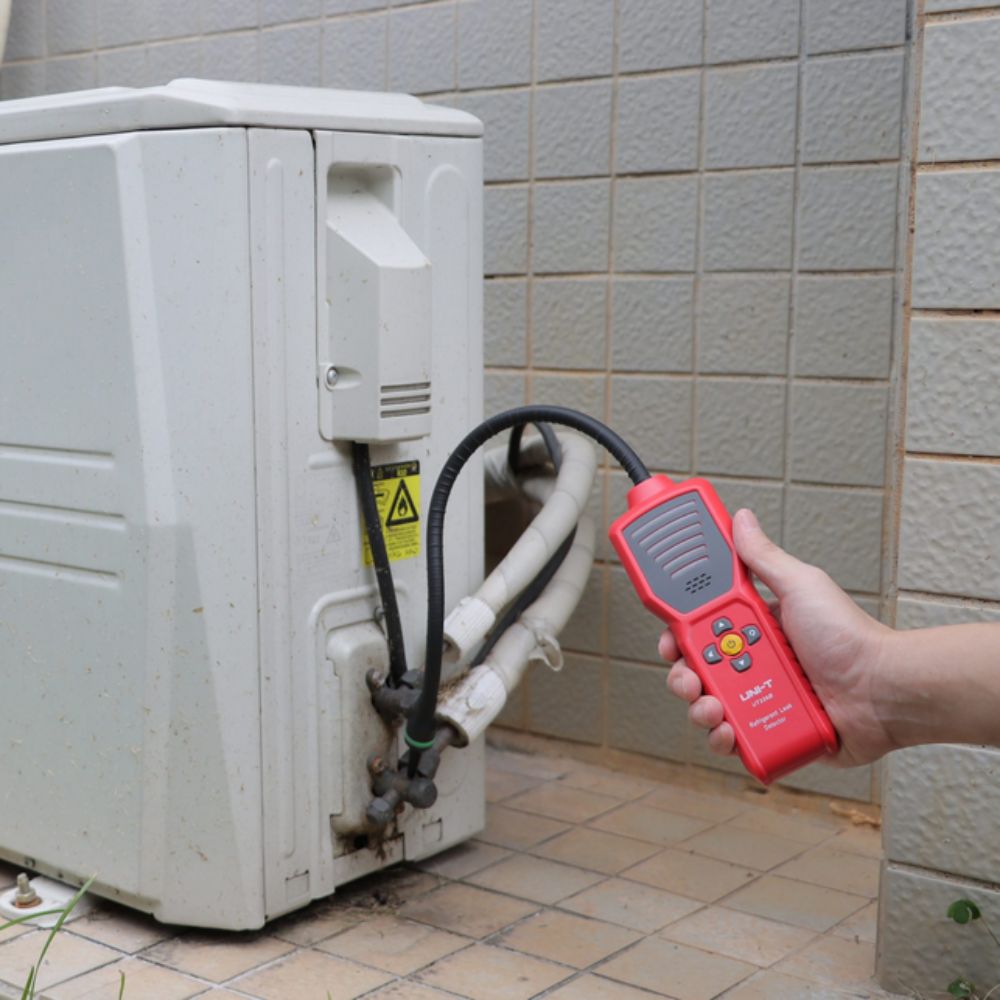 HVAC technician using the UT336B home AC freon leak detector to pinpoint R410a and R22 gas leaks on a residential outdoor condenser unit.