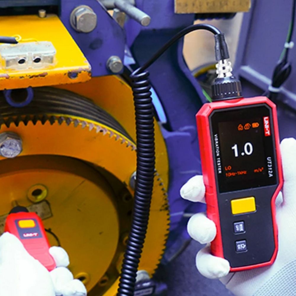 Maintenance technician using the UNI-T UT312A handheld vibration tester to measure mechanical vibrations and check for gear faults on an industrial transmission system.
