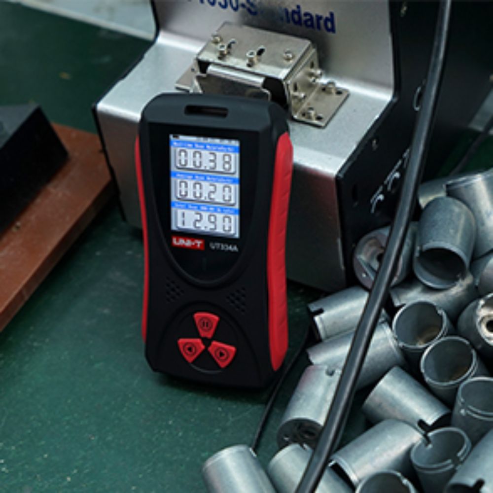 Safety officer performing a radiation survey on manufacturing machinery using the UNI-T UT334A dosimeter to monitor real-time dose rates in a factory.