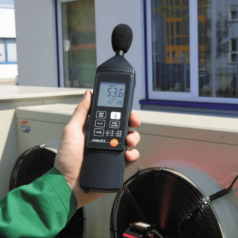 The testo 815 sound level meter being used to measure the ambient noise produced by an HVAC air conditioner outdoor unit.