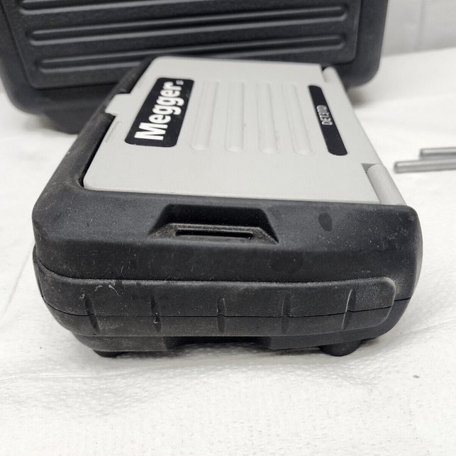 A side profile view of the rugged MEGGER DET3TD earth ground tester with its protective ash-colored front cover closed, ready for transport or storage.