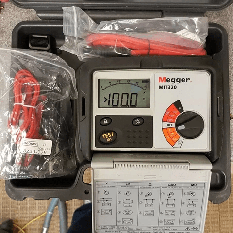 MEGGER MIT320 insulation tester neatly packed in carrying pouch showing 100 ohm reading, front cover opened with all accessories visible