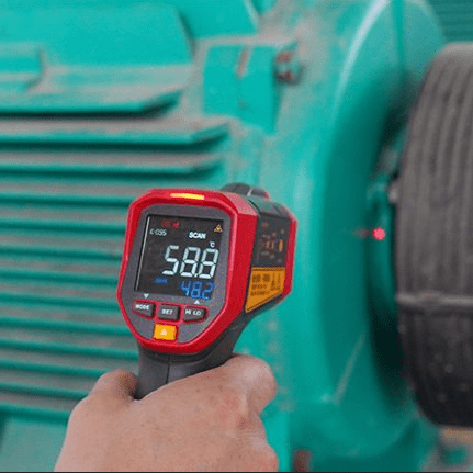 An electrical technician performs predictive maintenance by using the UNI-T UT305S non-contact pyrometer to check the bearing temperature of an industrial induction motor, reading 58.8°C to diagnose potential overheating and prevent failure.