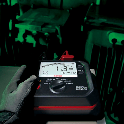 Technician using Sanwa MG5000 insulation tester to check a high voltage transformer, displaying an 11.3 gigaohm reading in 5000V range.