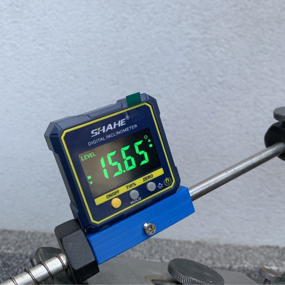 SHAHE 5315-90C magnetic digital angle gauge attached to metal rod measuring 15.65 degrees for pipe alignment welding and engineering angle checks.