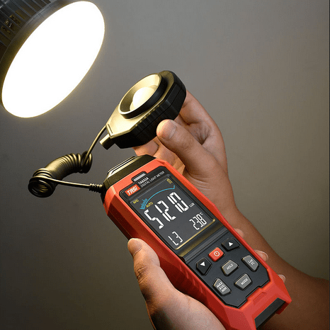 The TASI TA632B lux meter with its detachable, wired light sensor probe being used for remote light intensity measurement.