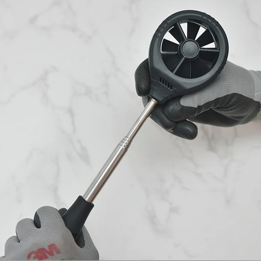 A close-up of a technician's hand holding the lightweight, easy-to-handle telescopic vane probe from the TASI TA642C anemometer.