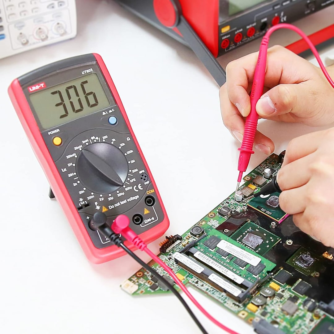 Technician Using UNI-T UT603 for Circuit Board Repair - Diagnosing Faulty PCB Components - Digital LCR Meter on 20mH Range Showing 306 Value - Electronic Maintenance and Fault Finding