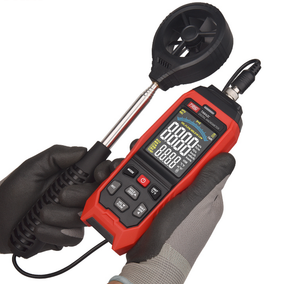A technician holding the TASI TA642C digital anemometer, with the probe connected and the device powered on, ready to perform an air velocity measurement.