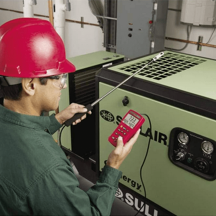 A technician using the AMPROBE TMA-21HW anemometer to measure air velocity at the ventilation grill of an industrial generator.