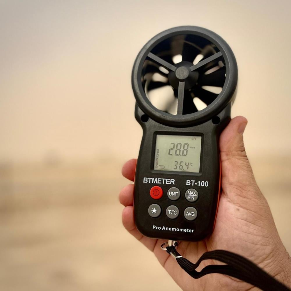 An HVAC technician uses the BTMETER BT-100 handheld anemometer to measure high-velocity air flow, with the digital display showing a 28.8 reading, demonstrating its use for professional wind testing.