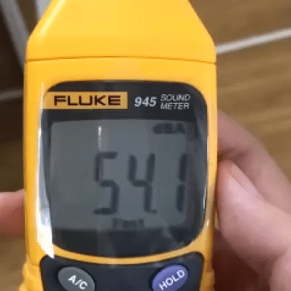 A technician conducting a live workplace noise assessment with the Fluke 945 sound level meter, which shows a reading of 54.1 dBA.