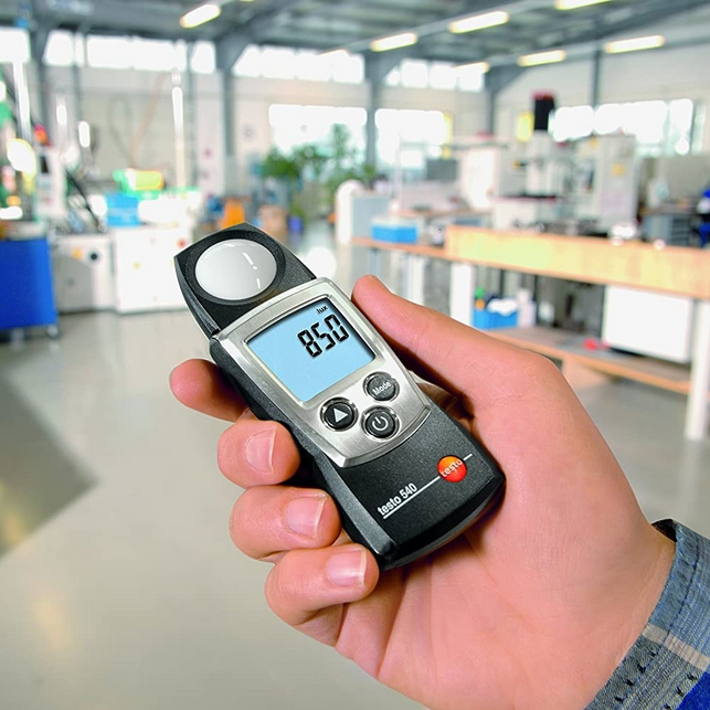 A technician using the TESTO 540 handheld light meter to conduct a precise spot check of ambient lighting in a professional lab environment.