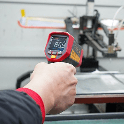 A technician using the handheld UNI-T UT305S laser thermometer for industrial inspection, accurately targeting and measuring a hot surface at 86.9°C from a safe distance to ensure operational safety and quality.