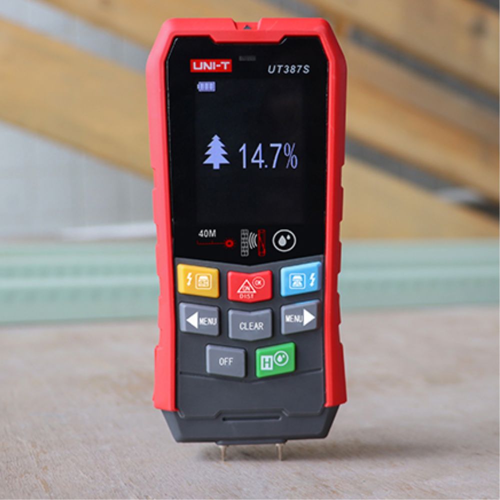 Building inspector using the UNI-T UT387S to perform a wood moisture test during a damp survey and wall condition inspection.