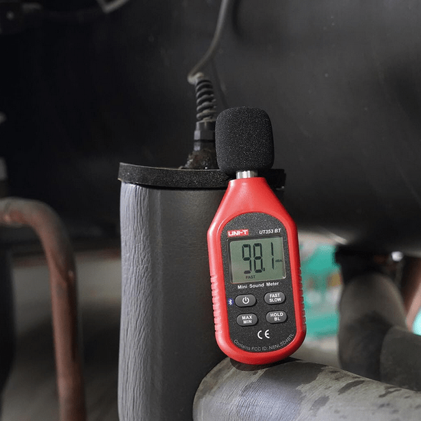 Measuring the operational noise level of a commercial HVAC air conditioning unit with the UNI-T UT353 sound meter, showing 98.1 dBA.
