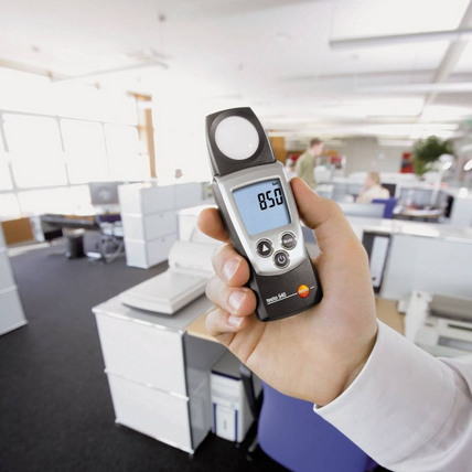 The TESTO 540 pocket lux meter being used to measure workplace lighting, showing an 850 Lux reading to ensure OHS compliance in an office.