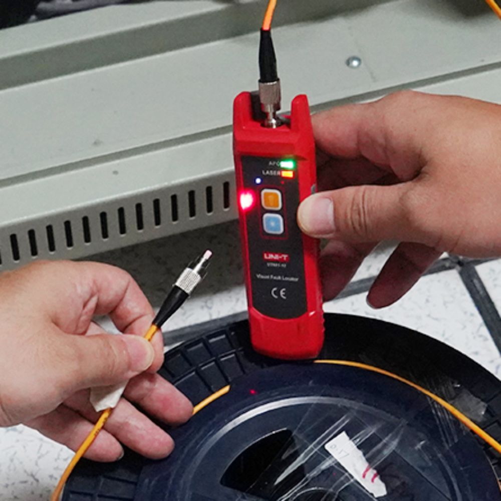 Technician using the UT691-01 visual fault locator to verify end-to-end continuity and detect damage on a fiber optic cable spool.