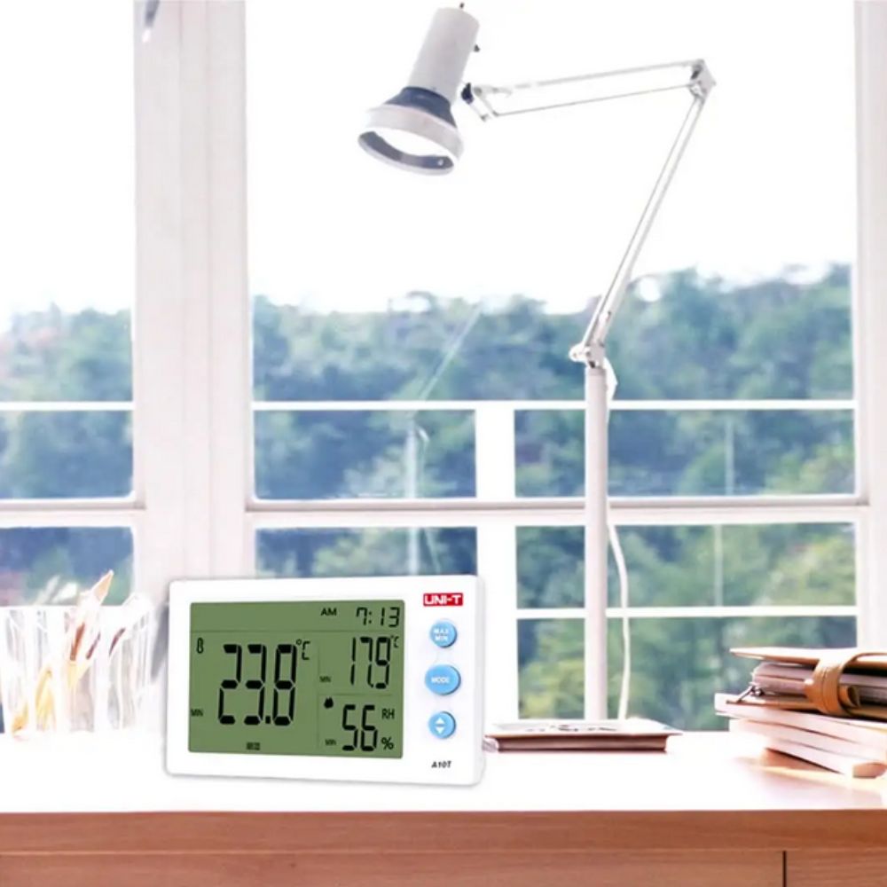 UNI-T A12T temperature and humidity meter on office desk in room, showing 23.8°C temperature and 56% RH, perfect indoor climate monitor for workplaces, study rooms and home offices.