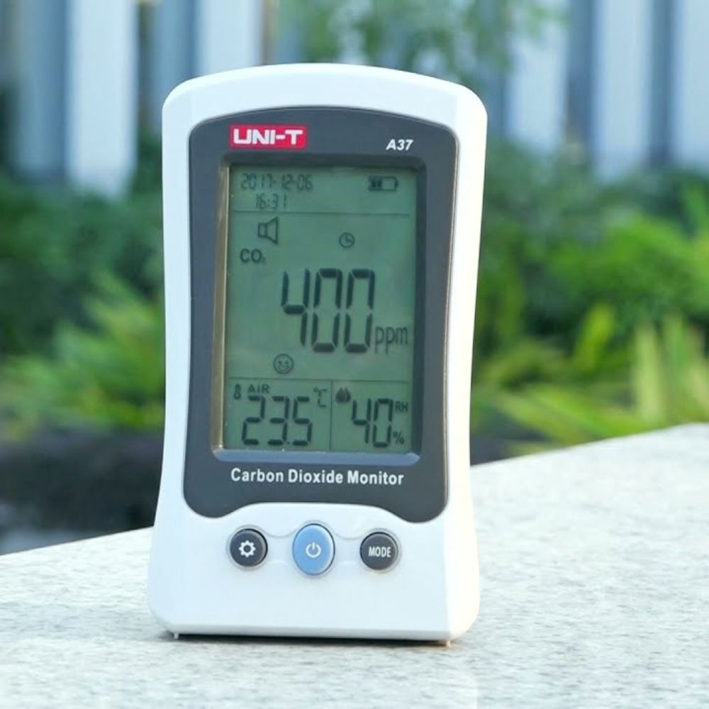 UNI-T A37 NDIR CO2 meter measuring carbon dioxide levels in an outdoor garden