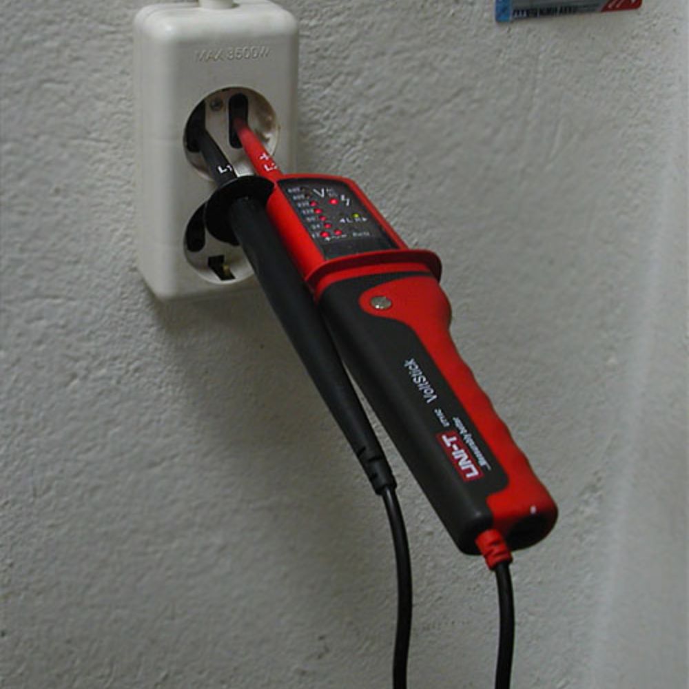 UNI-T UT15C line continuity tester safely measuring AC voltage and verifying circuit integrity on a standard residential wall power outlet.