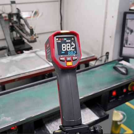 The UNI-T UT305S infrared thermometer mounted on a tripod for hands-free, continuous process monitoring, measuring the surface temperature of an industrial heating element at 88.2°C for quality control applications.
