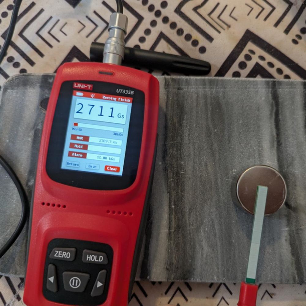 UNI-T UT335C testing powerful magnet, display reads 2711Gs with backlight on, ±1% accuracy for industrial magnet grading