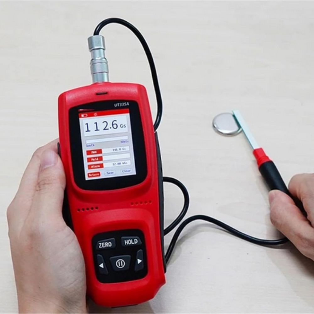 UNI-T UT335C gauss meter testing magnet, display shows 112.6Gs reading with backlight on, precise Hall probe in use