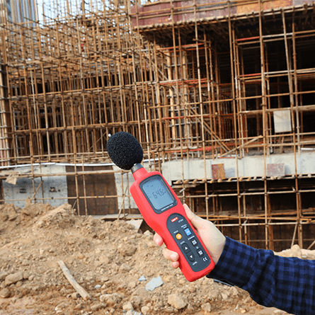 An environmental safety officer monitors noise on a construction site with the handheld UNI-T UT352 decibel meter for an accurate acoustic assessment.