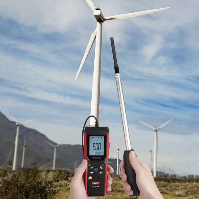 Technician using the UNI-T UT362H anemometer to measure wind speed in a wind turbine field, demonstrating its application for renewable energy and environmental testing.