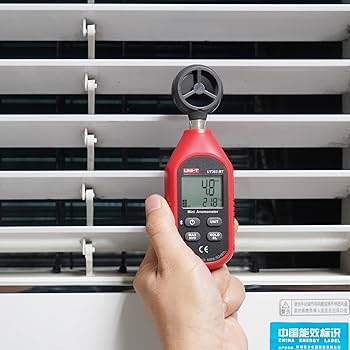 HVAC technician using the UNI-T UT363BT anemometer to measure air flow from a ventilation window, with the display showing a precise 4.8 m/s reading.