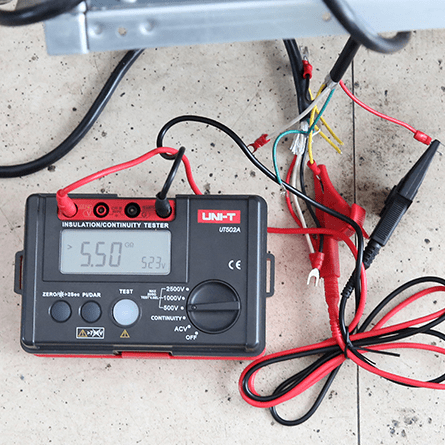 The UNI-T UT502A insulation resistance tester connected to household electrical wiring, displaying a 5.5 GΩ insulation reading.