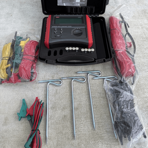 UNI-T UT572 Portable Earth Tester kit interior view showing organized test leads (40m, 20m, 10m, 5m), 4x auxiliary earth spikes, alligator clips, wire rolls, and complete ground measurement accessories