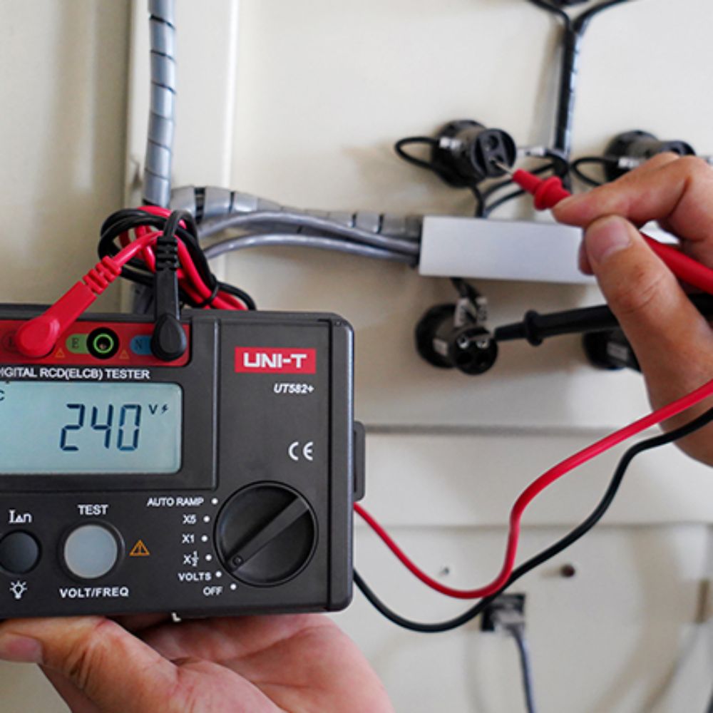 UNI-T UT582+ Digital ELCB Tester performing socket outlet RCD test on a wall plug base
