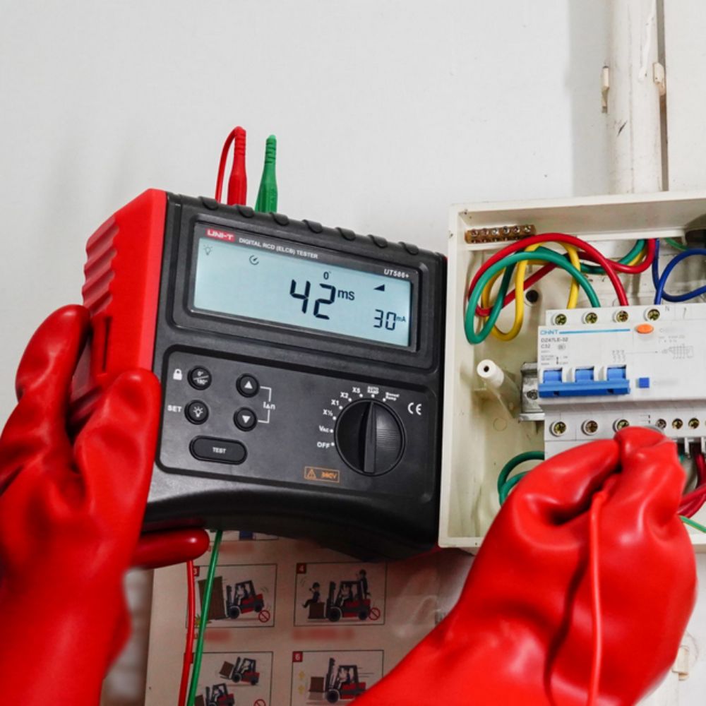 UNI-T UT586+ three-phase RCD tester performing loop impedance test on an electrical circuit breaker panel