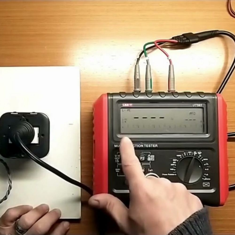 UNI-T UT593 multifunction electrical installation tester performing a test near a wall socket plug base