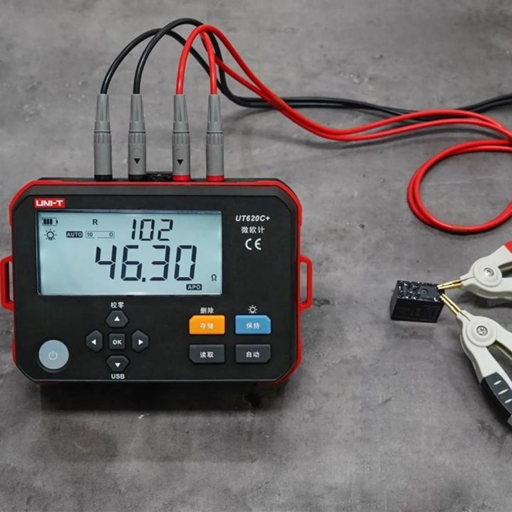 UNI-T UT620C+ digital micro ohm meter measuring the resistance of an electronic component using four-wire test leads.