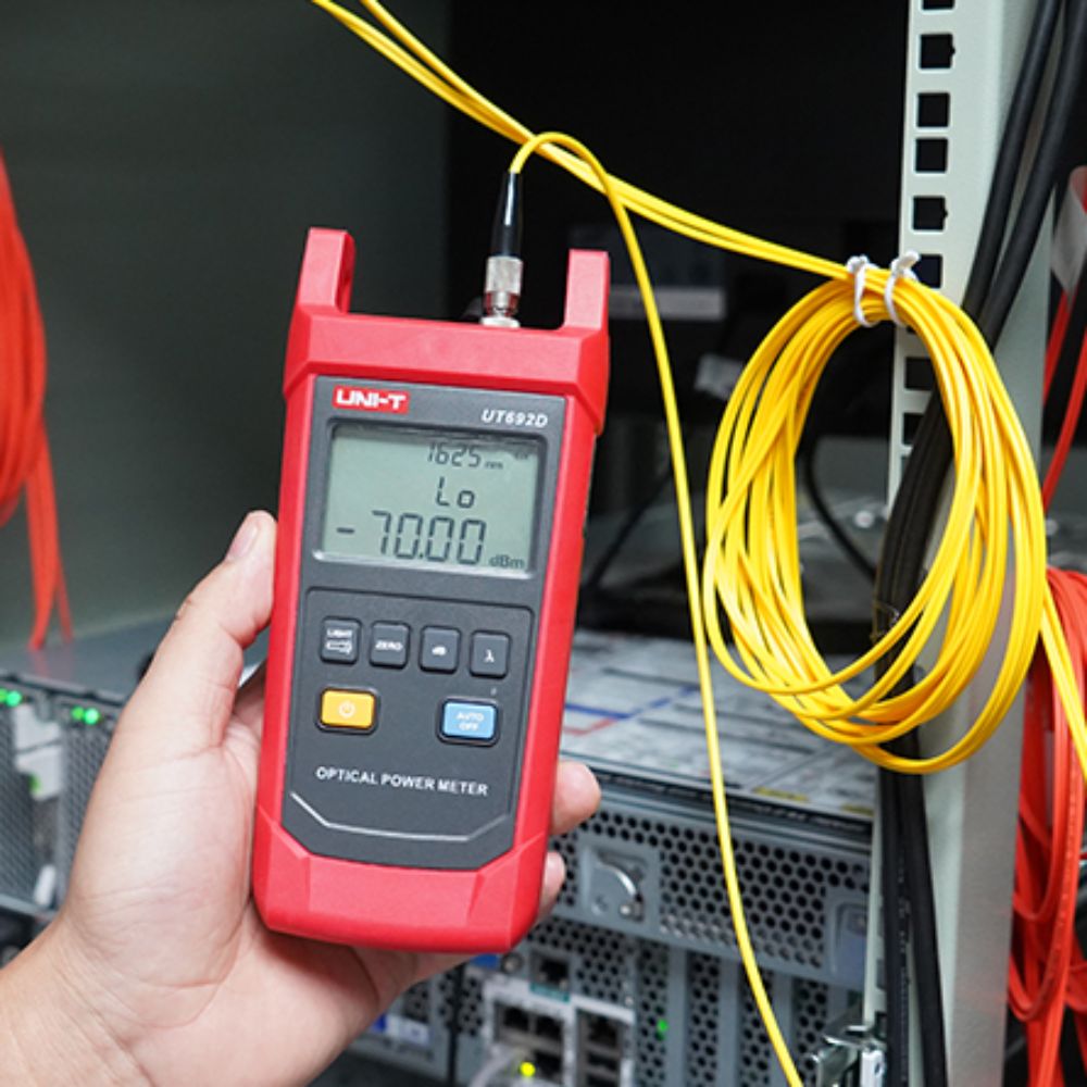 Technician using the UT692G high-range power meter to accurately measure absolute optical power on a fiber transmission line.